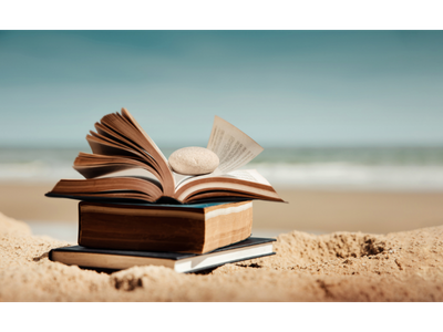 a stack of books on a sandy beach. 